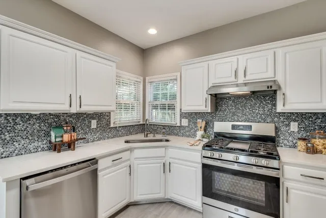 a kitchen with granite countertop a sink stove and cabinets