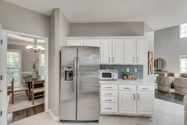 a kitchen with white cabinets and refrigerator