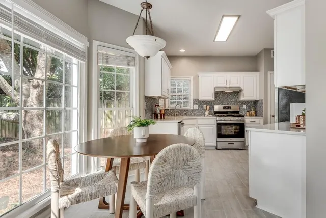 a kitchen with stainless steel appliances granite countertop a stove a refrigerator a kitchen island a stove and a dining table with wooden floor