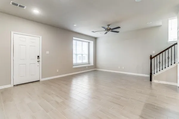 an empty room with wooden floor ceiling fan and windows