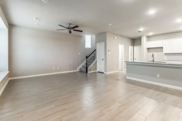 an empty room with wooden floor and a kitchen view