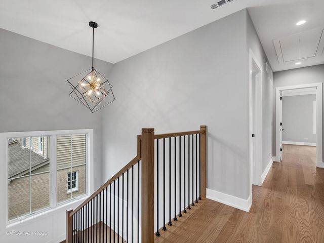 a view of a hallway with wooden floor and chandelier