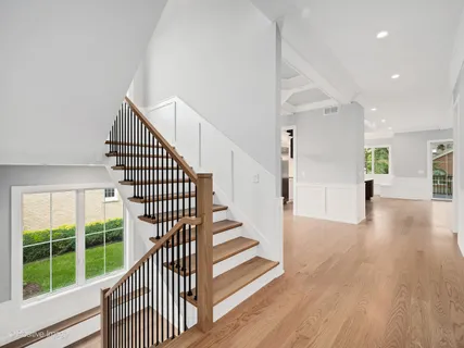 a view of a hallway with wooden floor windows and stairs
