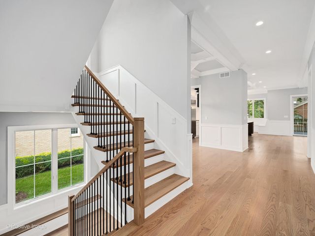 a view of a hallway with wooden floor windows and stairs