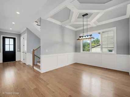 a view of an empty room with wooden floor kitchen view and a window