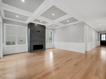 an empty room with wooden floor fireplace and windows