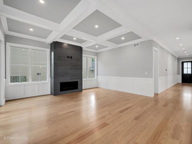 an empty room with wooden floor fireplace and windows