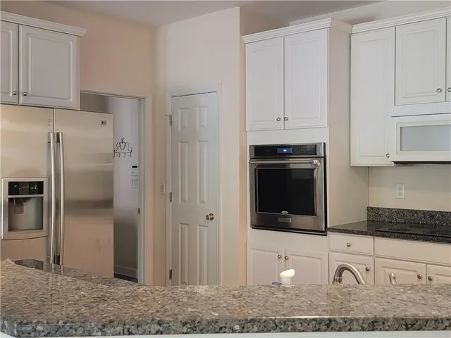 a kitchen with granite countertop white cabinets and stainless steel appliances
