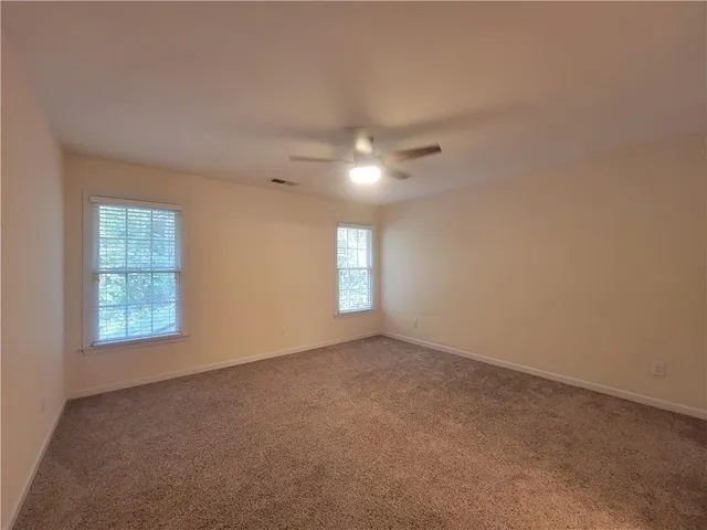an empty room with windows and chandelier fan