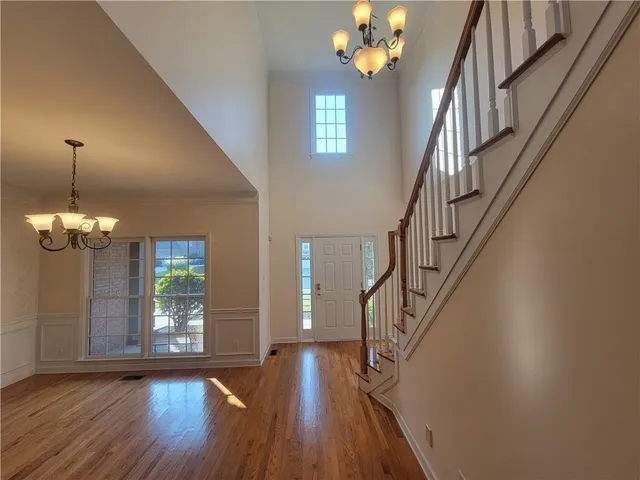 a view of a room with wooden floor chandelier and windows