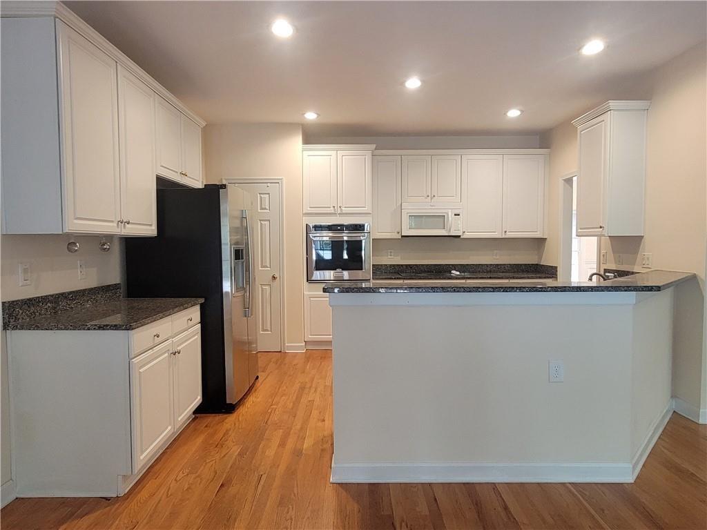 6330 Olde Atlanta Parkway Suwanee, GA 30024 - Photo 10 of 31 a kitchen with stainless steel appliances a refrigerator a stove top oven and white cabinets
