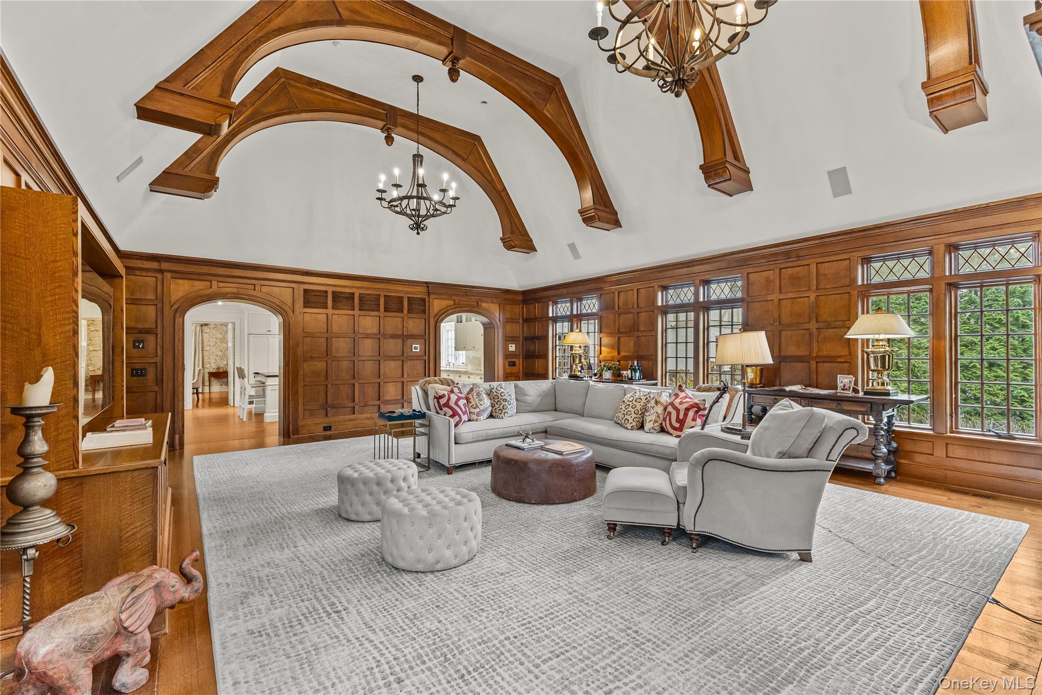 19 Park Drive South Rye, NY 10580 - Photo 19 of 42 Living area featuring hanging chandeliers, a high ceiling, arched walkways, built in shelves, and rich wood paneled walls.