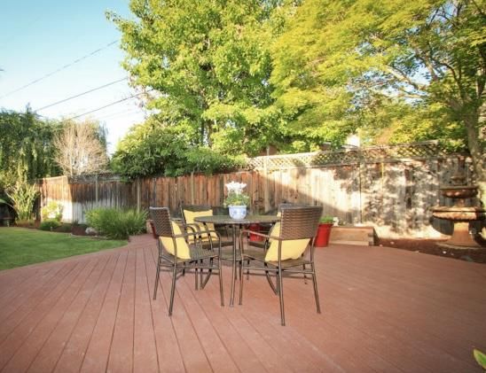 a view of a patio with table and chairs with wooden floor and fence