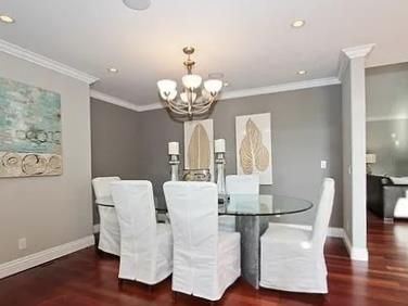 a dining room with wooden floor a chandelier a glass table and chairs