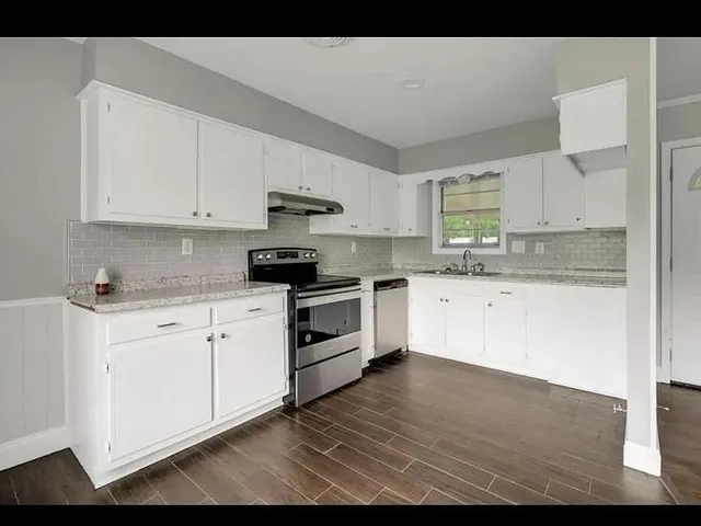 a kitchen with granite countertop white cabinets and white appliances