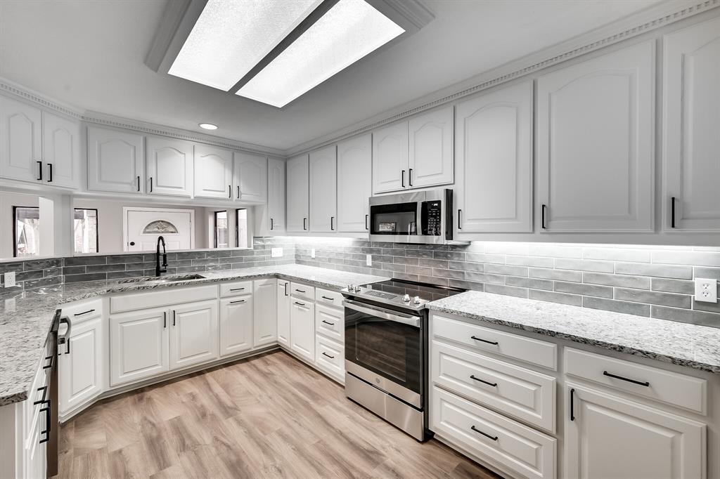 a kitchen with granite countertop white cabinets white stainless steel appliances and sink