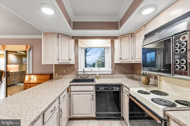 a kitchen with kitchen island granite countertop a sink and white cabinets