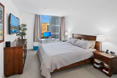 a bedroom with a bed and a flat tv screen on dresser