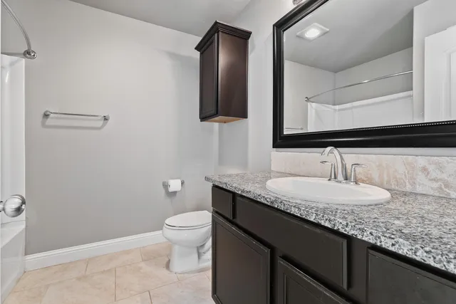 a bathroom with a granite countertop sink a toilet and mirror