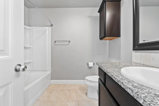 a bathroom with a granite countertop sink a toilet and bathtub