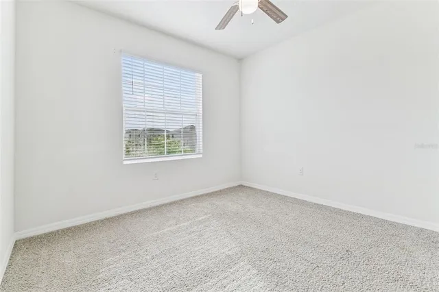 an empty room with closet and a ceiling fan