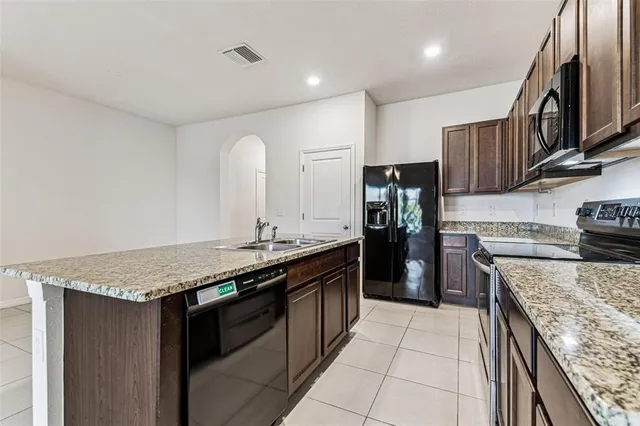 a kitchen with a granite countertop sink a counter top space and cabinets