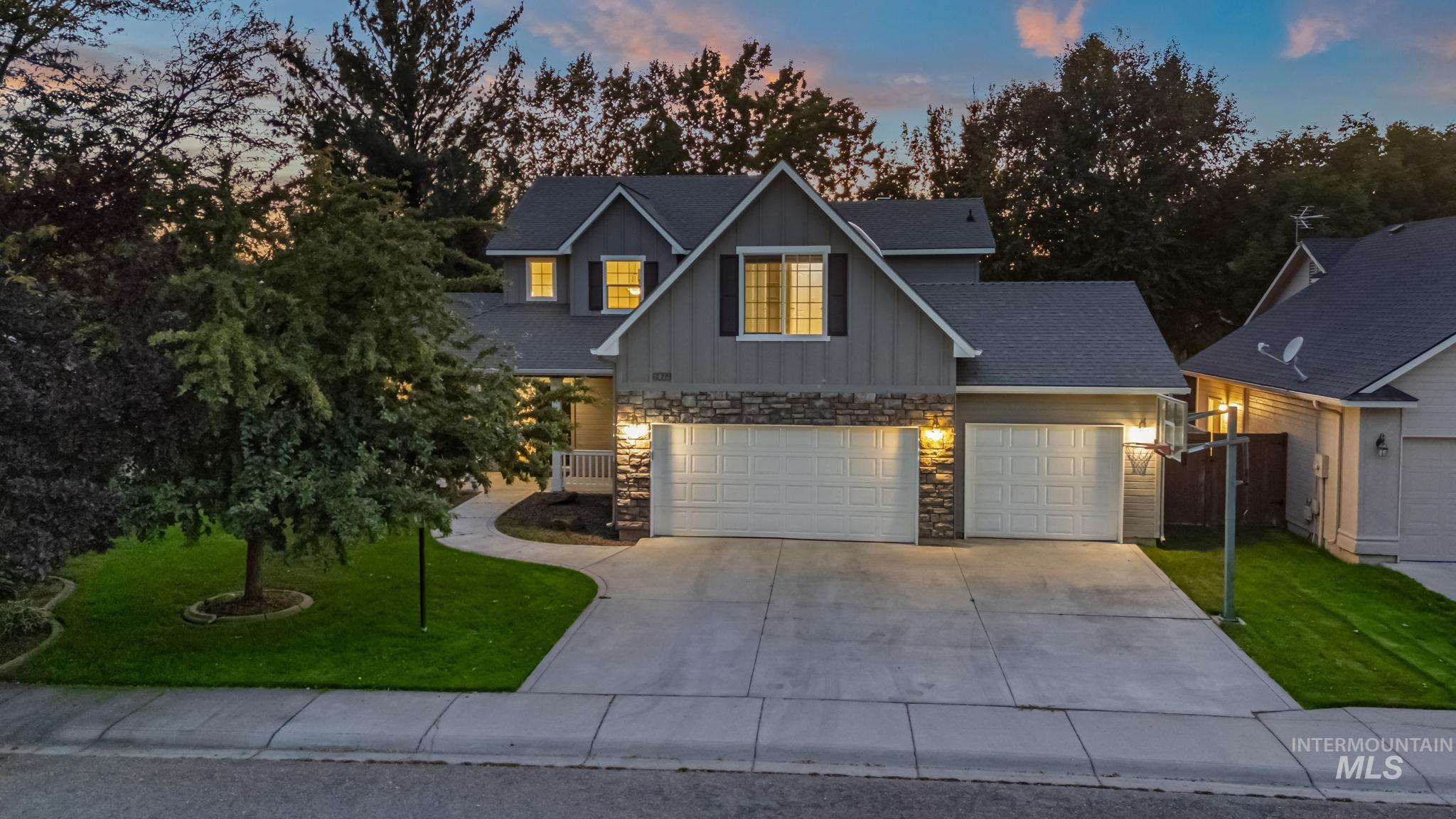 Traditional home featuring a yard, board and batten siding, stone siding, and concrete driveway