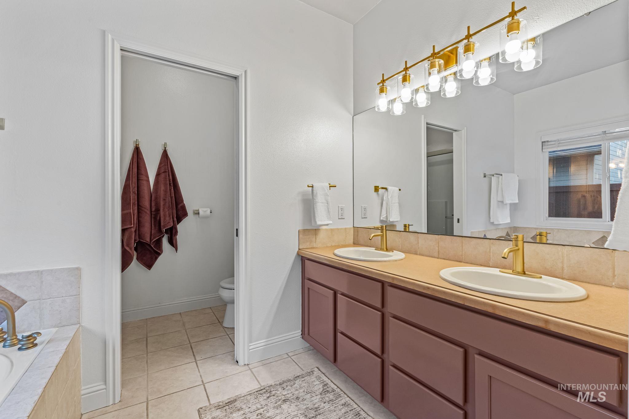 6099 North Heathrow Way Boise, ID 83713 - Photo 17 of 39 Full bathroom with double vanity, a garden tub, and light tile patterned floors