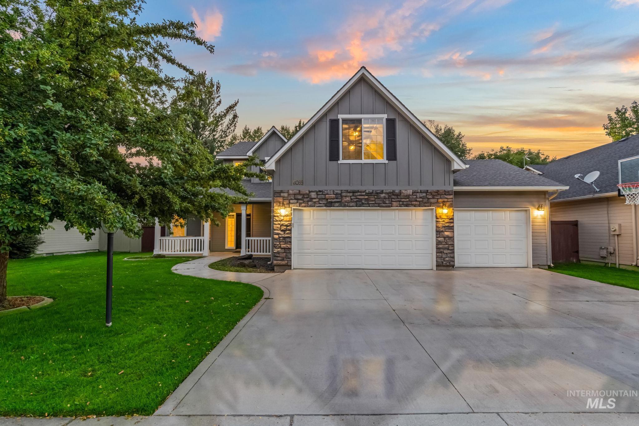 6099 North Heathrow Way Boise, ID 83713 - Photo 2 of 39 View of front of home featuring board and batten siding, a lawn, driveway, stone siding, and an attached garage