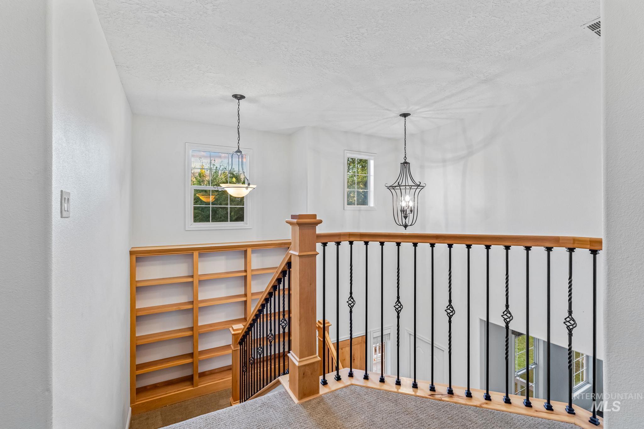 6099 North Heathrow Way Boise, ID 83713 - Photo 21 of 39 Staircase featuring a textured ceiling and a chandelier