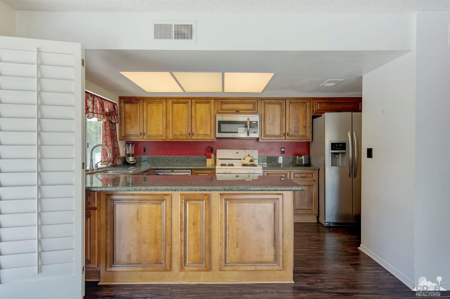 73769 Haystack Road Palm Desert, CA 92260 - Photo 16 of 34 a kitchen with stainless steel appliances granite countertop a stove and a refrigerator