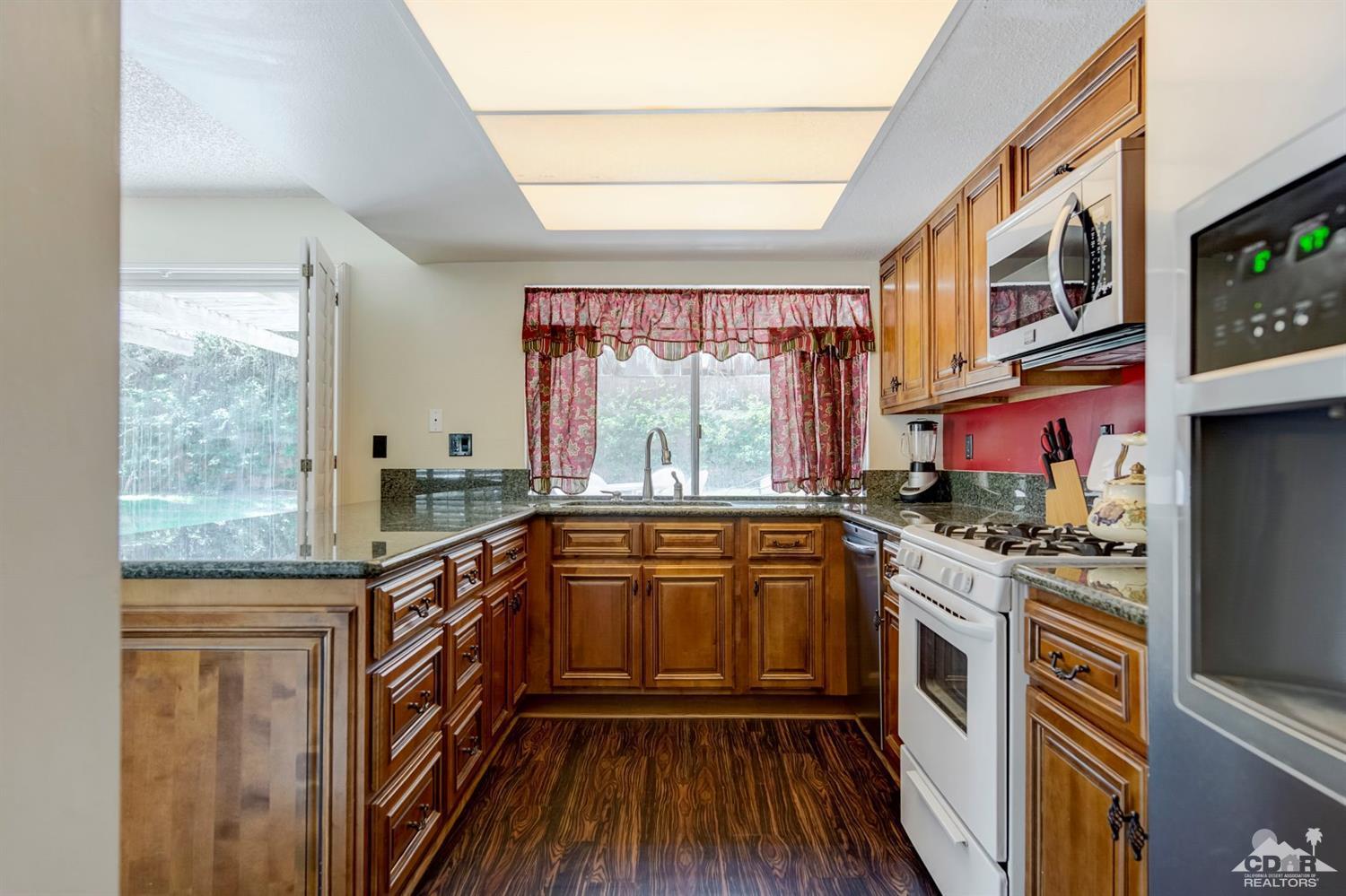 73769 Haystack Road Palm Desert, CA 92260 - Photo 17 of 34 a kitchen with stainless steel appliances granite countertop a stove a sink and a refrigerator
