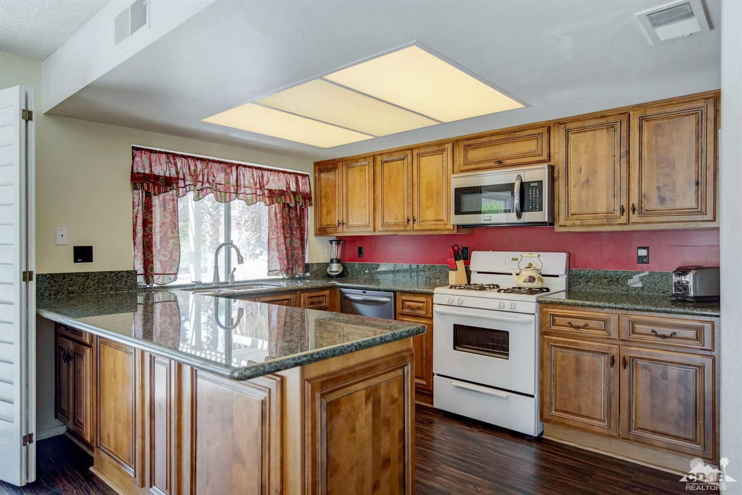 73769 Haystack Road Palm Desert, CA 92260 - Photo 3 of 34 a kitchen with stainless steel appliances granite countertop a stove a sink and a microwave