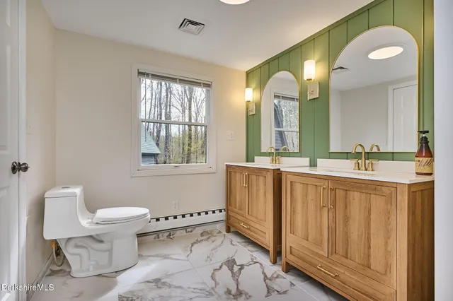 a bathroom with a double vanity sink mirror and toilet