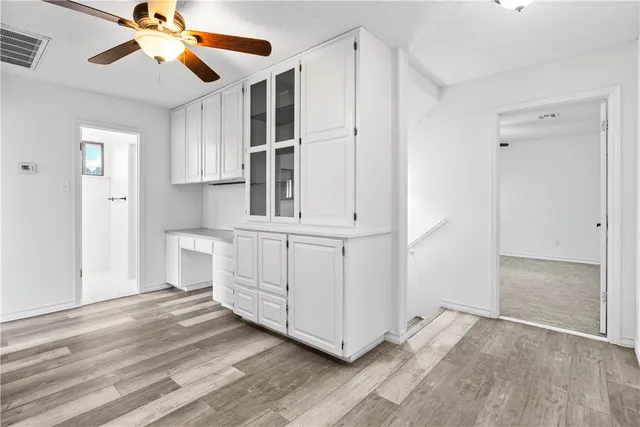 a view of empty room with wooden floor and fan