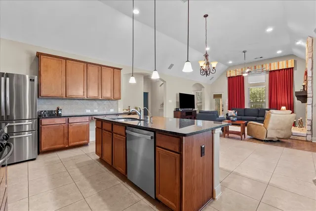 a kitchen with stainless steel appliances granite countertop a sink a stove and a wooden cabinets