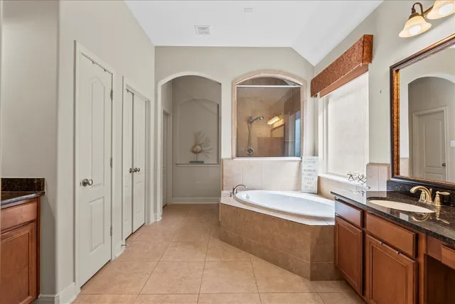a bathroom with a tub a mirror and shower in it