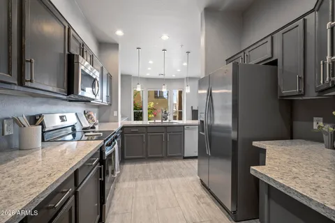 a kitchen with stainless steel appliances granite countertop a refrigerator a stove and a sink