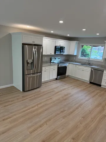 a large kitchen with stainless steel appliances granite countertop a refrigerator and a stove