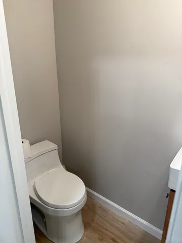 a white toilet sitting next to a wooden cabinet