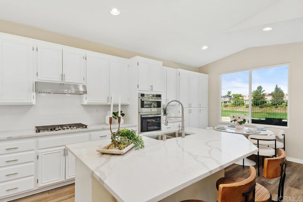 46056 Paseo Gallante Temecula, CA 92592 - Photo 9 of 41 a kitchen with stainless steel appliances a stove a sink and white cabinets with wooden floor