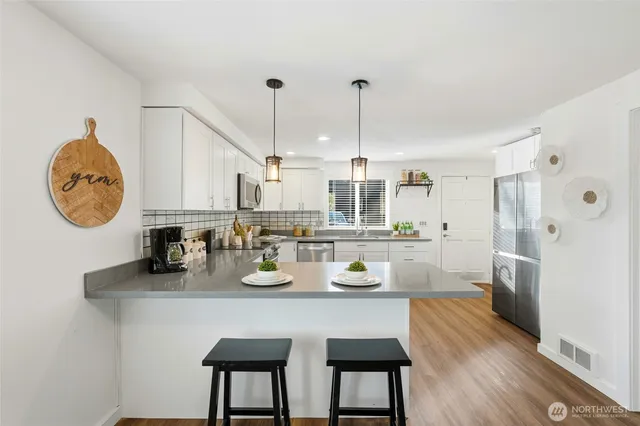 a kitchen with stainless steel appliances granite countertop a sink a stove refrigerator and cabinets with wooden floor