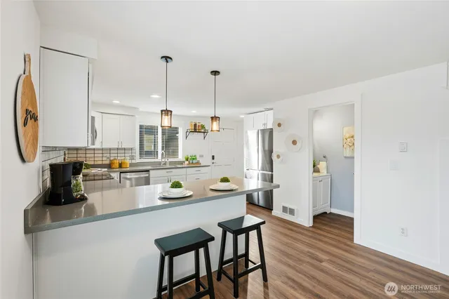 a kitchen with a sink a stove a refrigerator and white cabinets with wooden floor