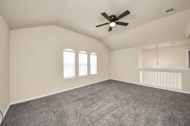 an empty room with ceiling fan and windows