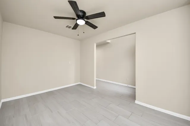 an empty room with wooden floor and ceiling fan