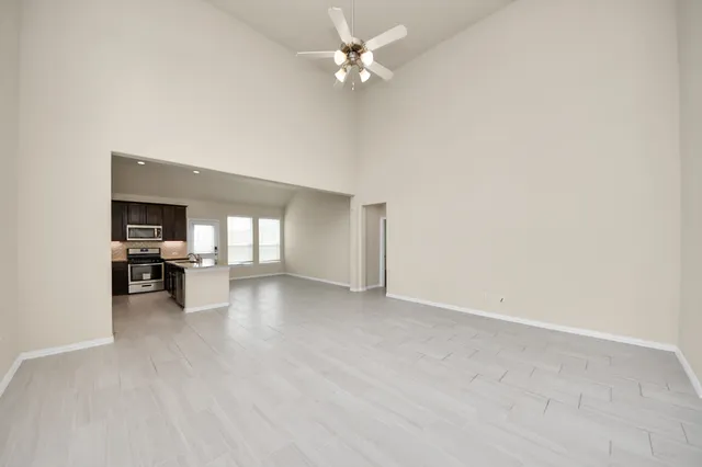 an empty room with fireplace and a ceiling fan