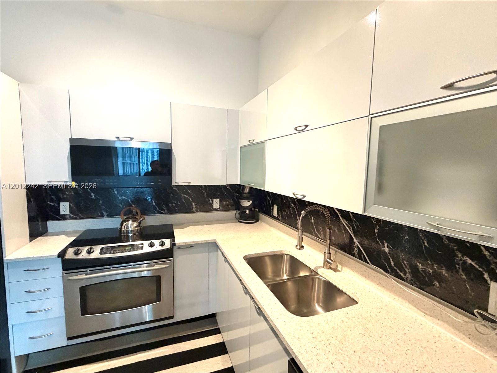 234 Northeast 3rd Street, Unit 1908 Miami, FL 33132 - Photo 3 of 16 a kitchen with granite countertop a stove and a sink