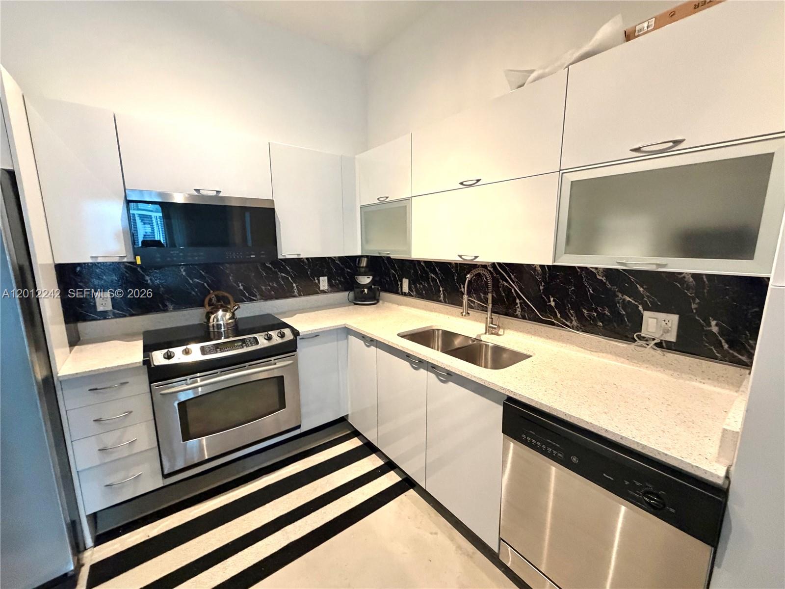 234 Northeast 3rd Street, Unit 1908 Miami, FL 33132 - Photo 4 of 16 a kitchen with granite countertop a sink and a stove