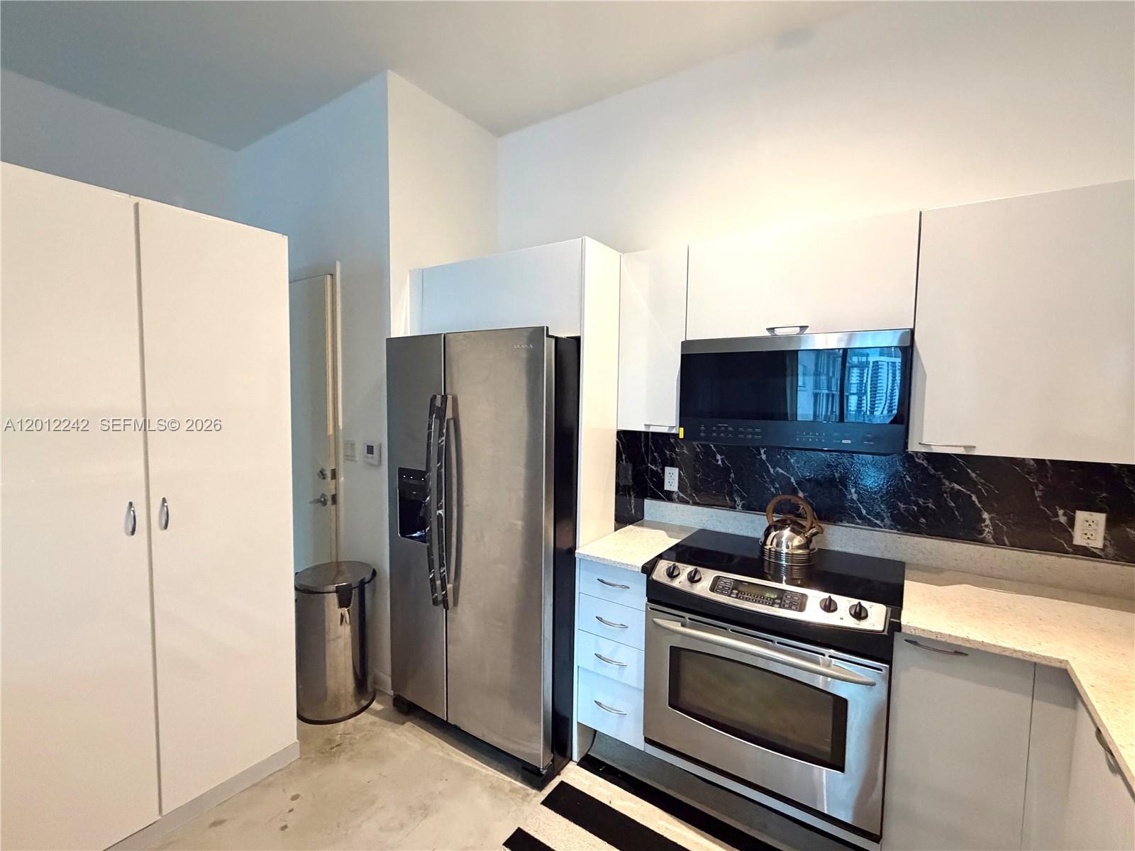 234 Northeast 3rd Street, Unit 1908 Miami, FL 33132 - Photo 6 of 16 a kitchen with stainless steel appliances granite countertop a refrigerator a stove and a sink with wooden cabinets