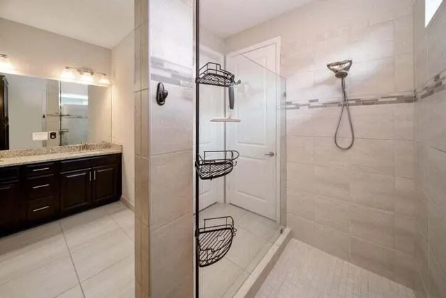 a bathroom with a granite countertop shower a sink and a mirror